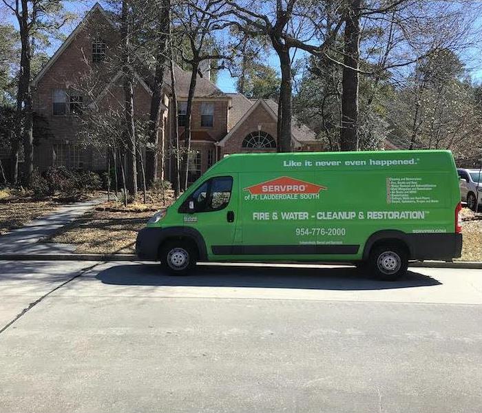 green SERVPRO van sitting on the road in front of a home