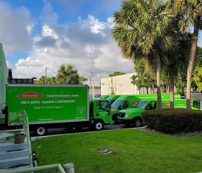 green SERVPRO box trucks and vans in a parking lot
