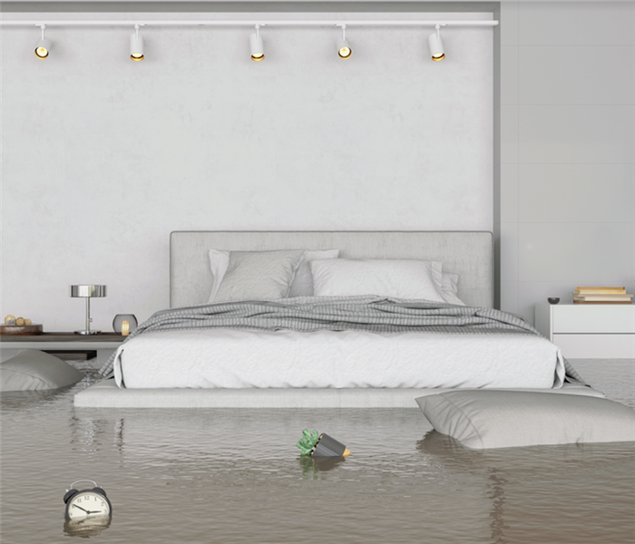 a flooded bedroom with water up to the bed and furniture floating around