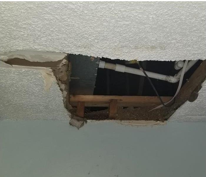 water damaged ceiling; drywall torn away to repair source of damage