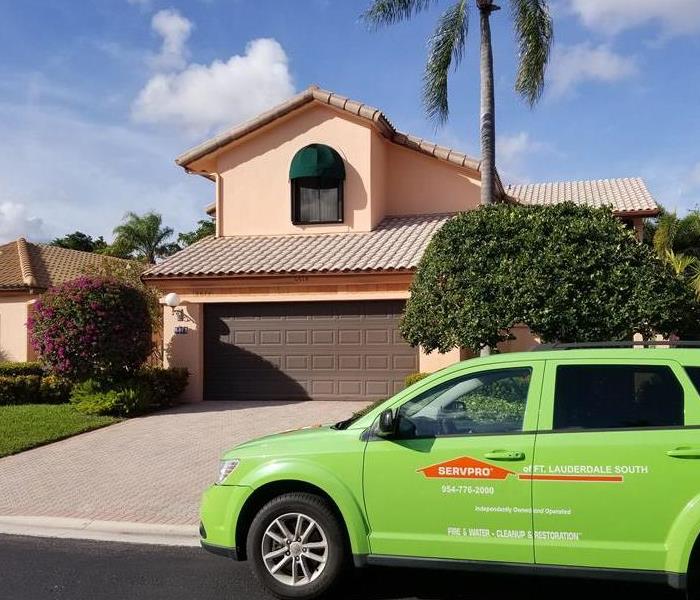 A green SERVPRO vehicle in front of a home